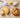A pale cookie made with powdered sugar next to a chocolate chip cookie made with granulated sugar, with spoons of each sugar above.