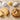 A pale cookie made with powdered sugar next to a chocolate chip cookie made with granulated sugar, with spoons of each sugar above.