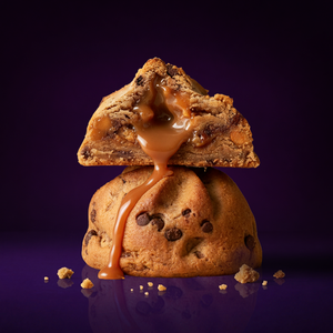 Chip N Drip chocolate chip cookie with gooey salted caramel core on purple background by Fat & Weird Cookie