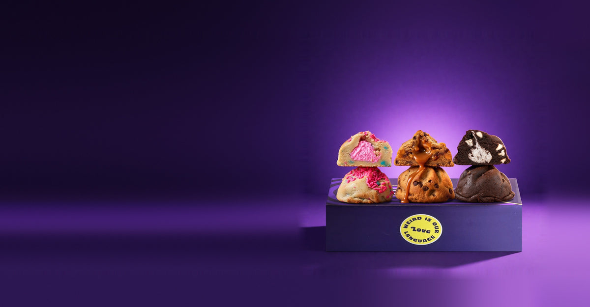 Three stuffed cookies cut in half on a Fat & Weird box on purple