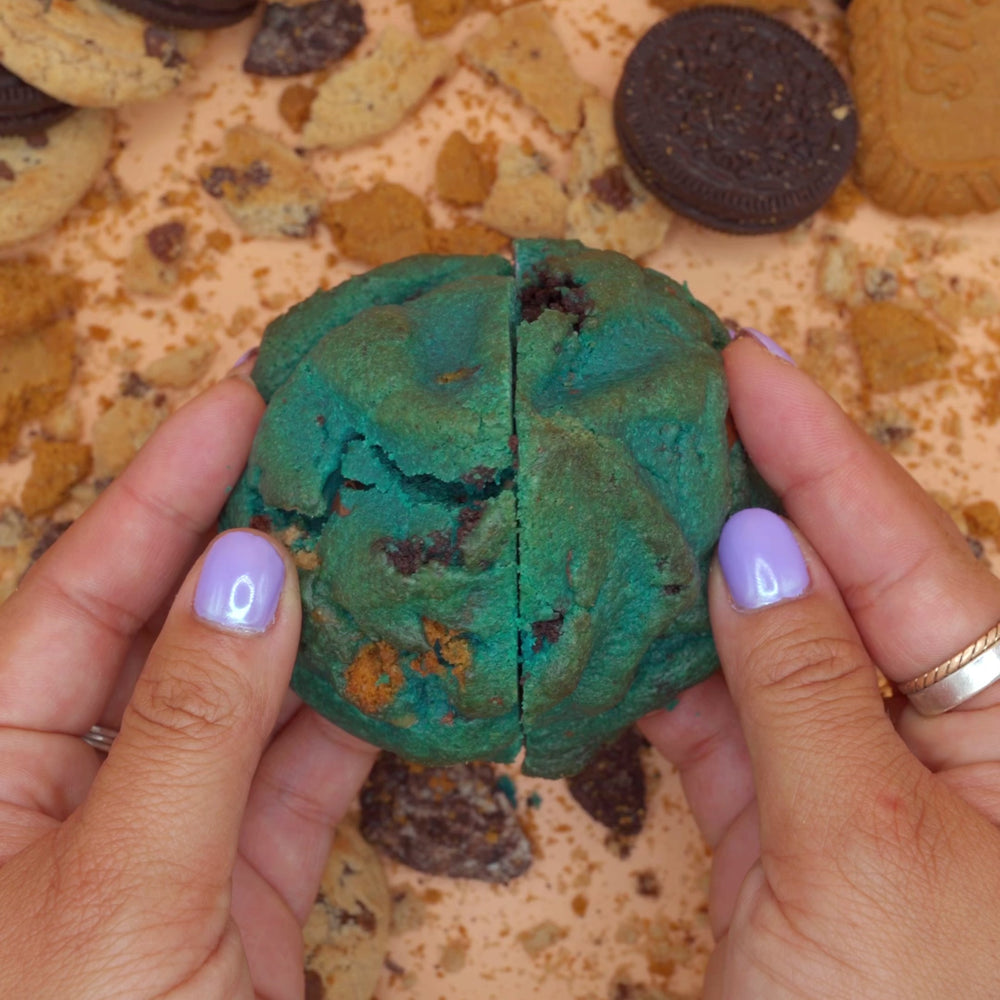 Hands breaking open Cookies Anonymous loaded cookie with cookie butter frosting center 