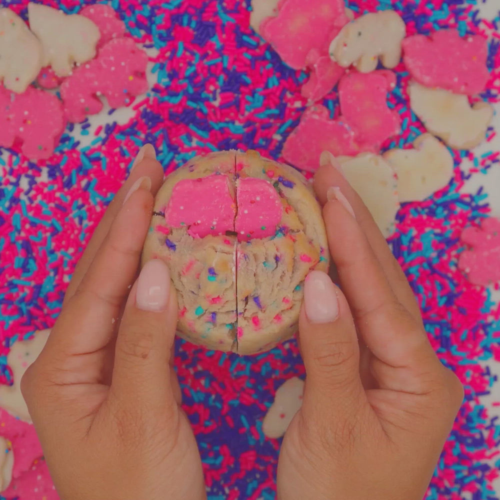 Hands breaking a Party Animal cookie revealing its blue buttercream frosting center