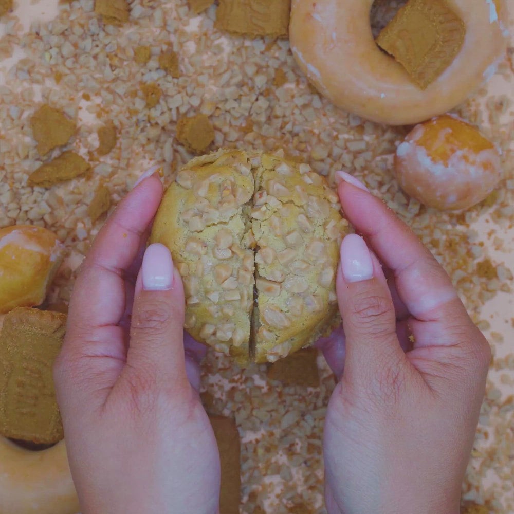 Hands breaking apart cookie butter donut stuffed cookie with cookie butter center
