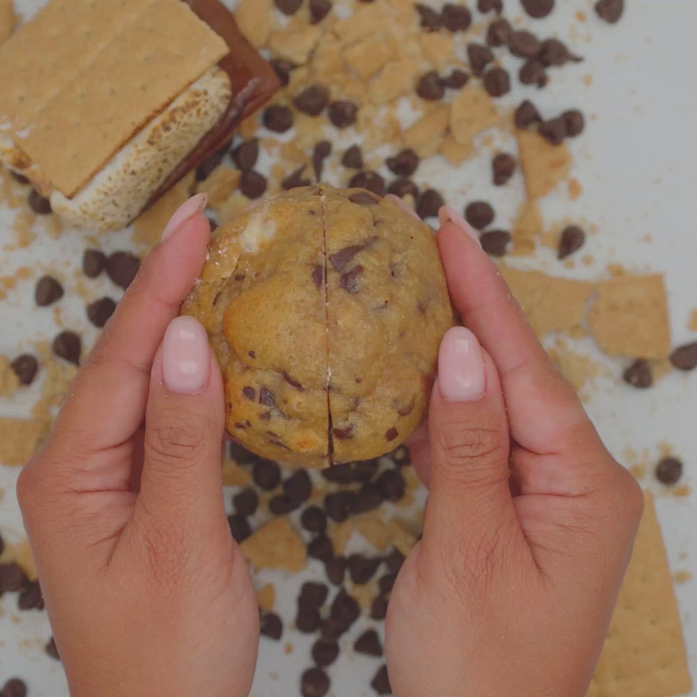 Hands breaking Some Mores cookie to reveal its gooey marshmallow center