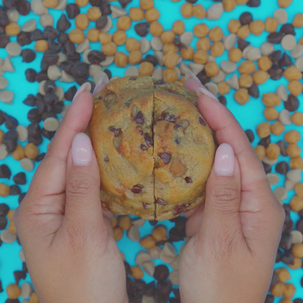 Hands pulling apart a Chip N Drip cookie to reveal a salted caramel center